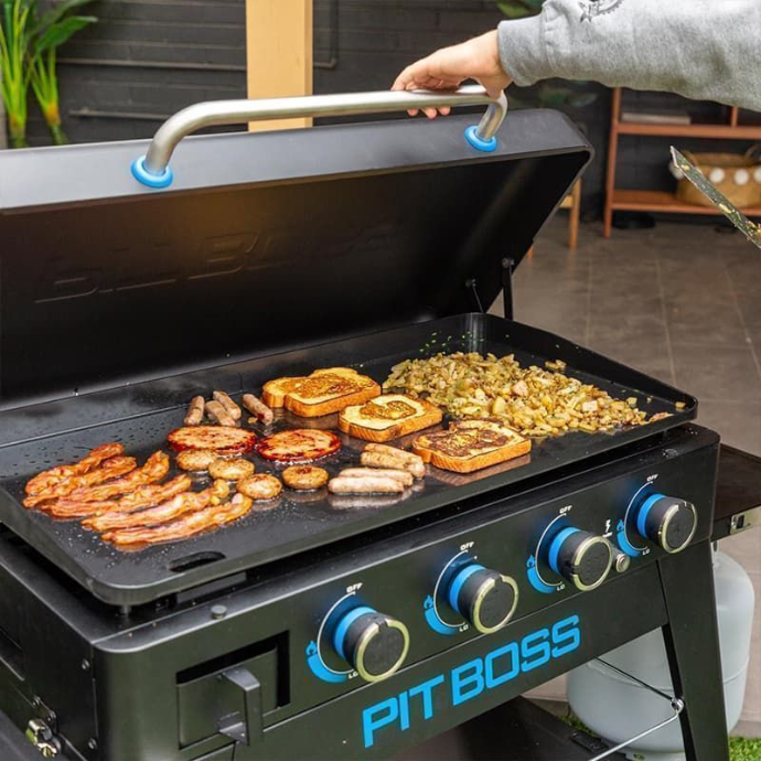 Bacon, sausages, eggs, and toast cooking on a large multi-burner Pit Boss gas flat-top griddle